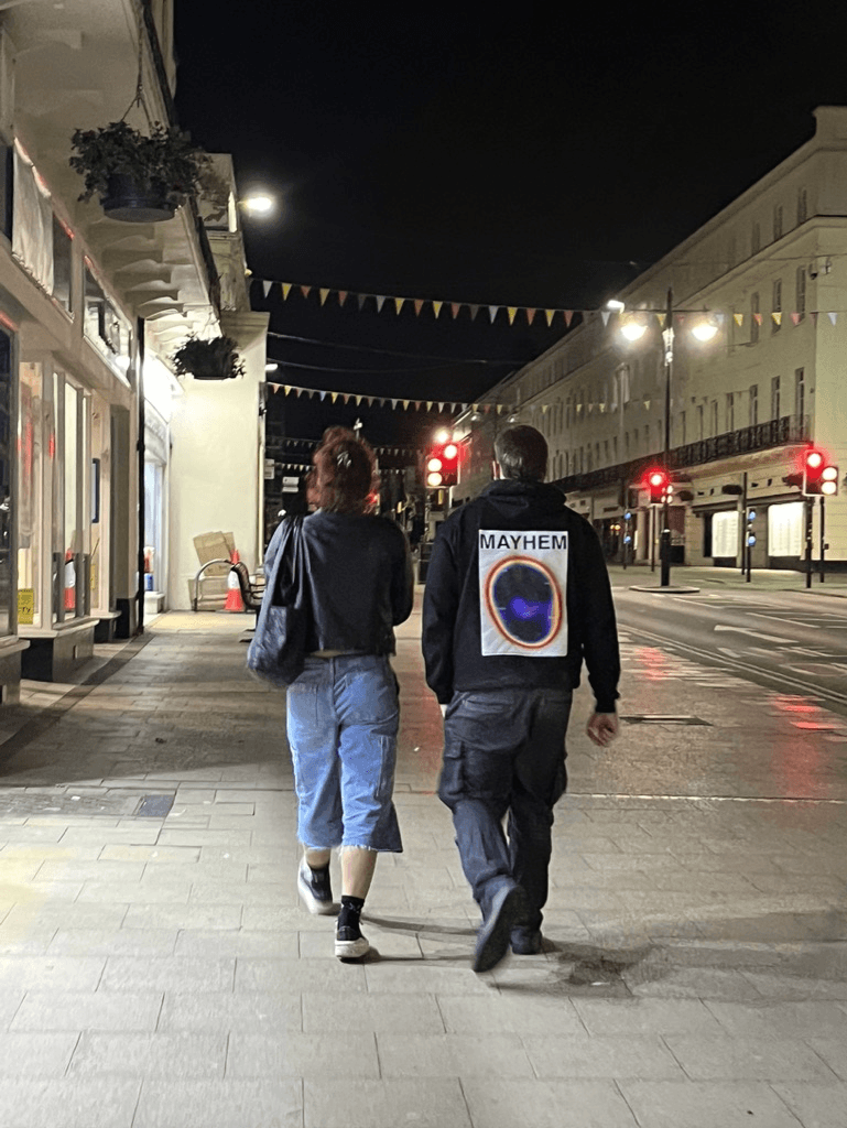 Person wearing a Mayhem hoodie in the street at night